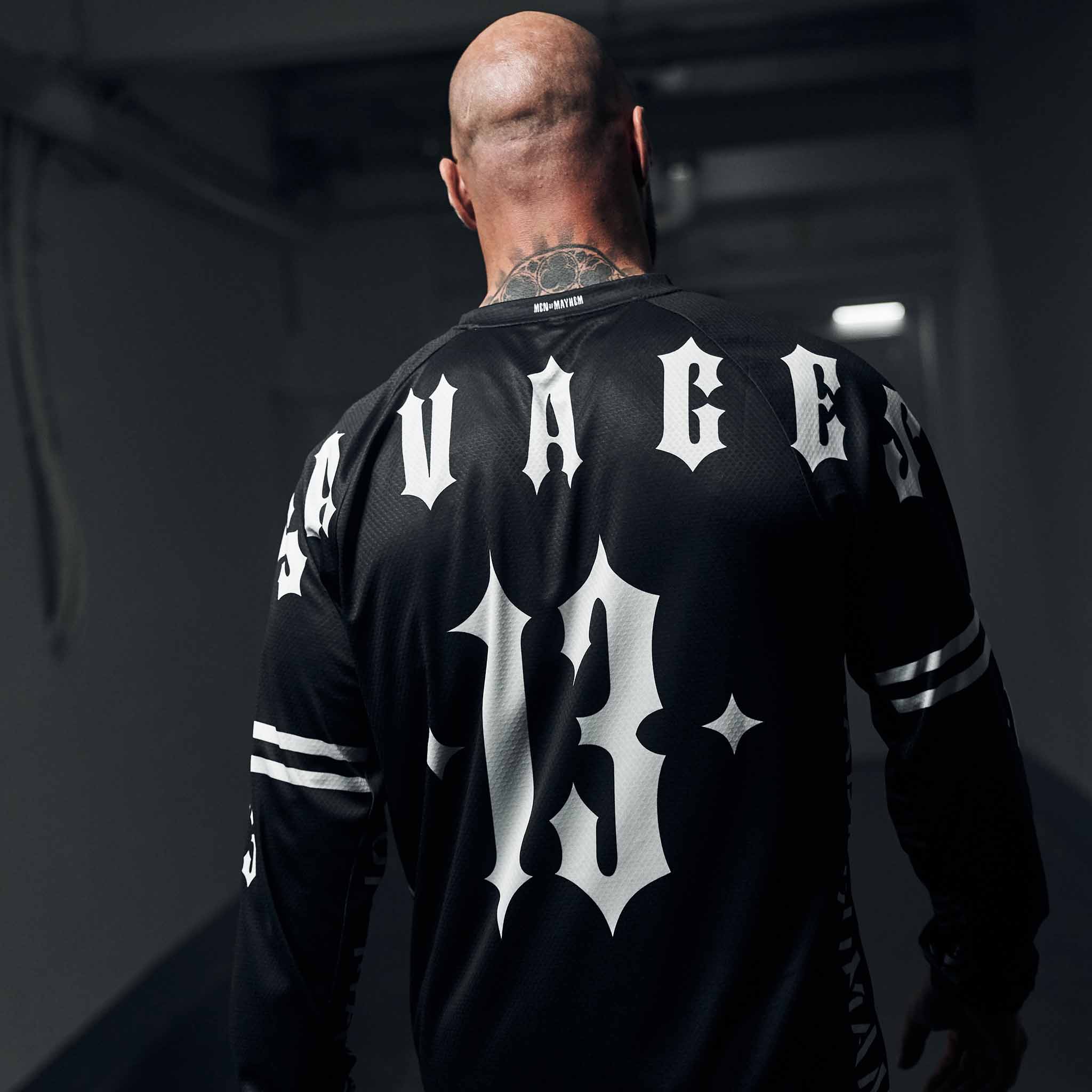 mann trägt schwarzes men of mayhem jersey mit weißem savages aufdruck über den rücken