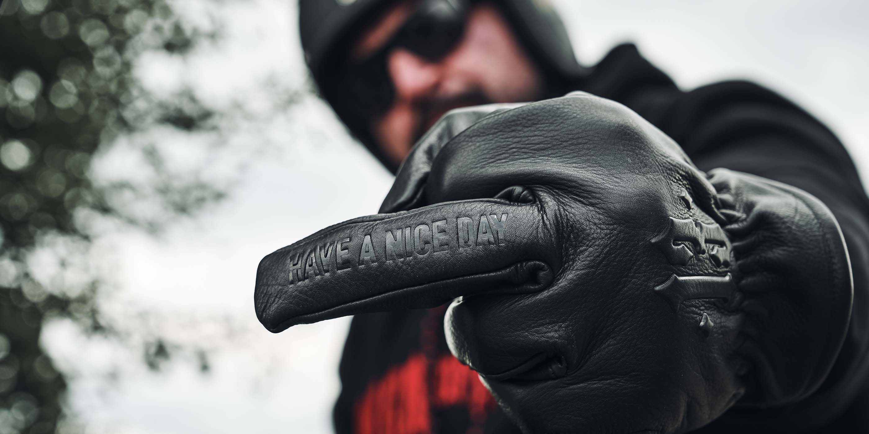 mann trägt lederhandschuh in schwarz aus leder und zeigt mittelfinger