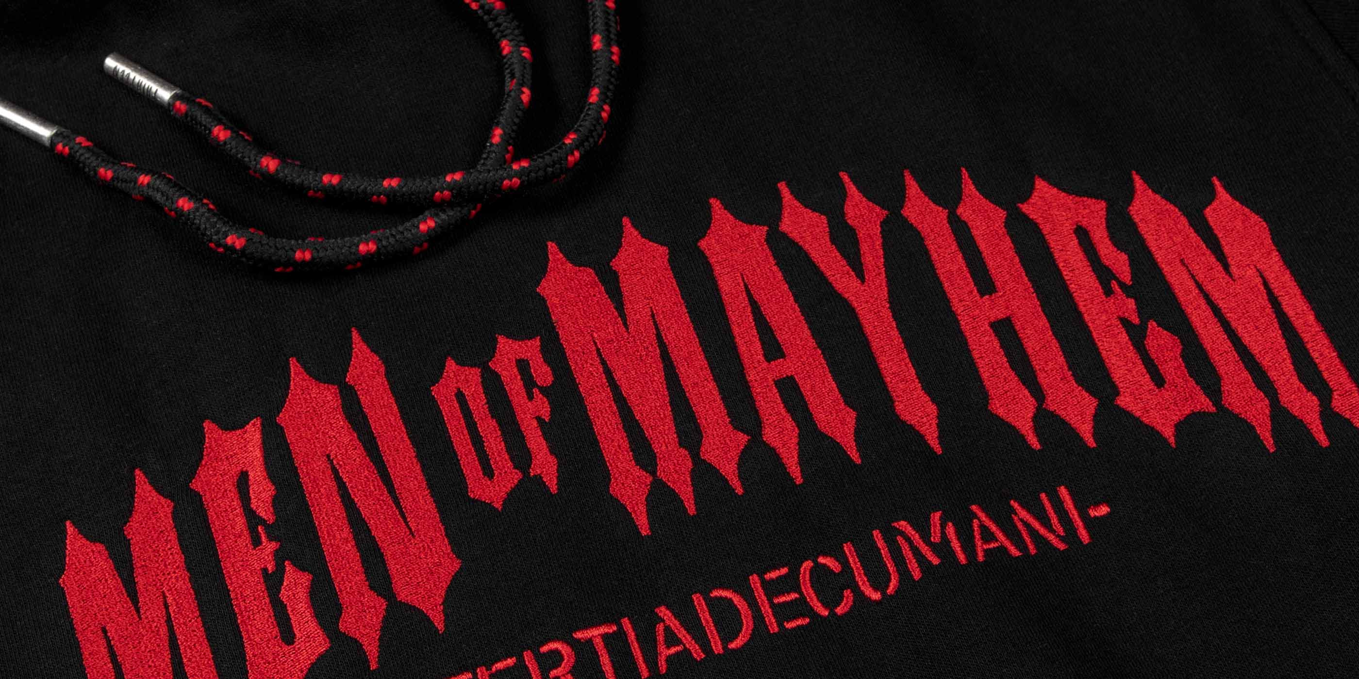 Nahaufnahme eines men of mayhem classic hoodies in schwarz mit rotem logo stick über die brust