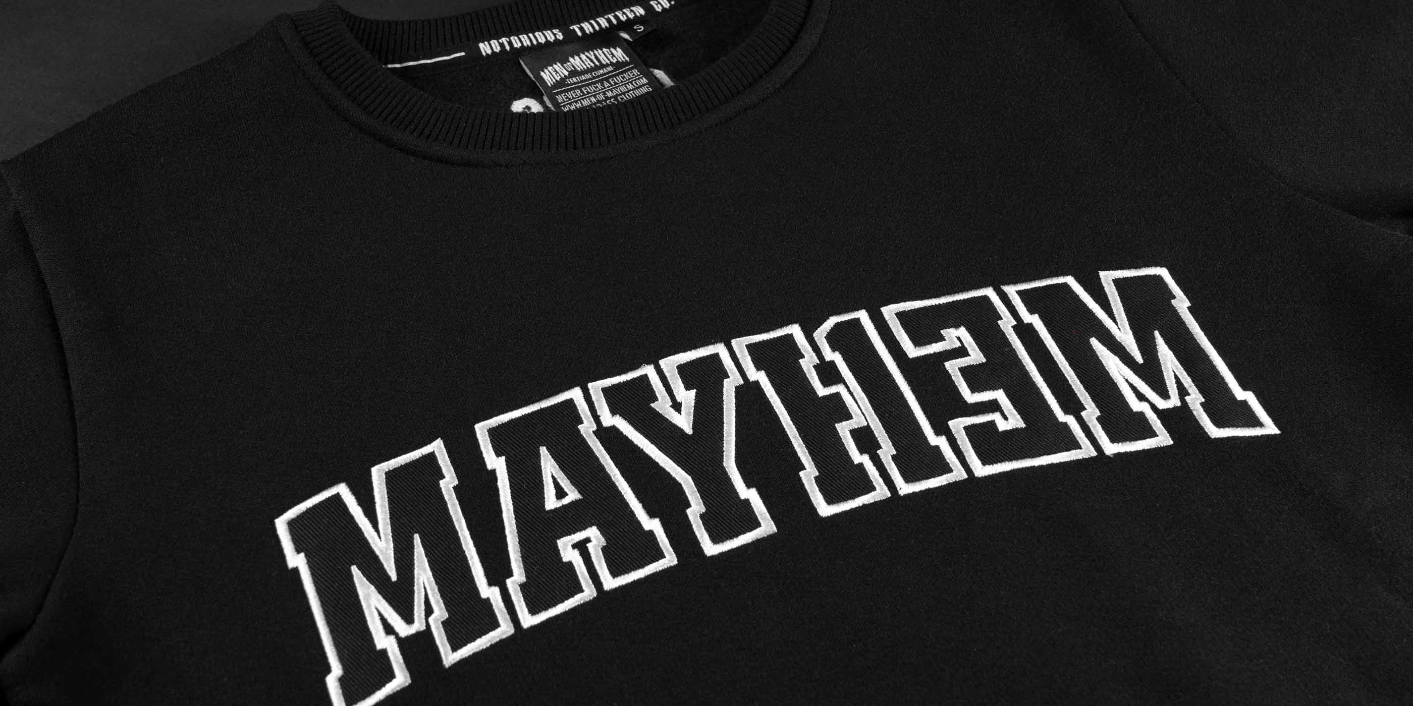 nahaufnahme eines men of mayhem league crewnecks in schwarz mit schwarz weisser aufschrift als applikation