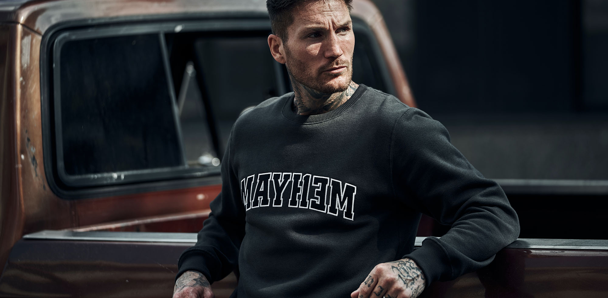 mann stehend am pickup truck trägt men of mayhem league crewneck in grau schwarz