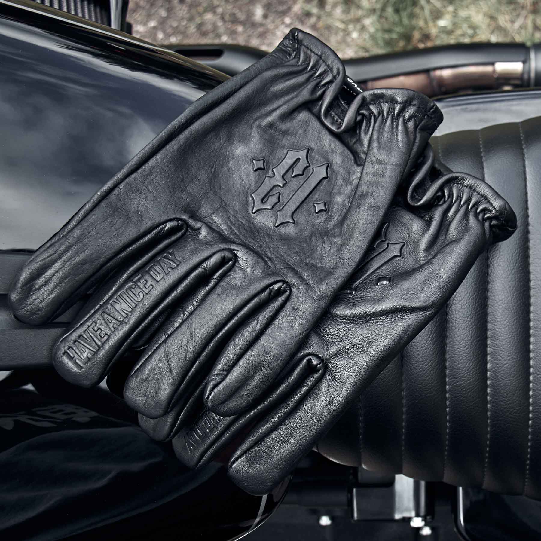 schwarze lederhandschuhe von men of mayhem mit geprägter 13 für motorrad liegend auf sitzbank eines motorrads