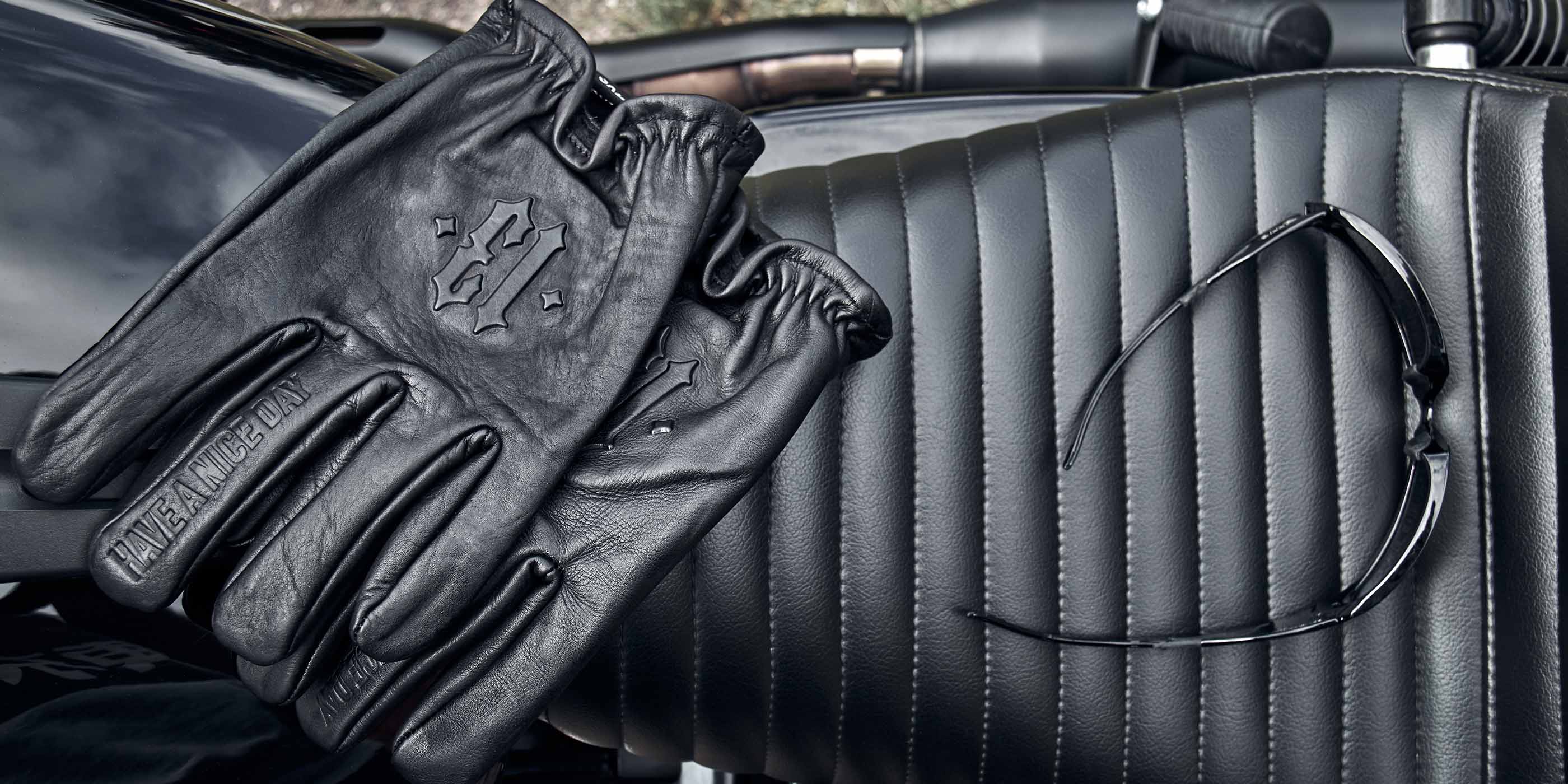schwarze lederhandschuhe von men of mayhem mit geprägter 13 für motorrad liegend auf sitzbank eines motorrads