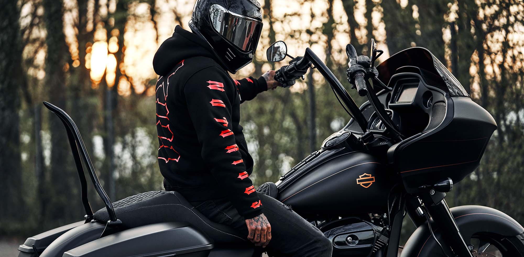 mann sitzend auf harley davidson trägt men of mayhem notorious thirteen hoody in schwarz mit rotem druck auf den ärmeln und dem rücken