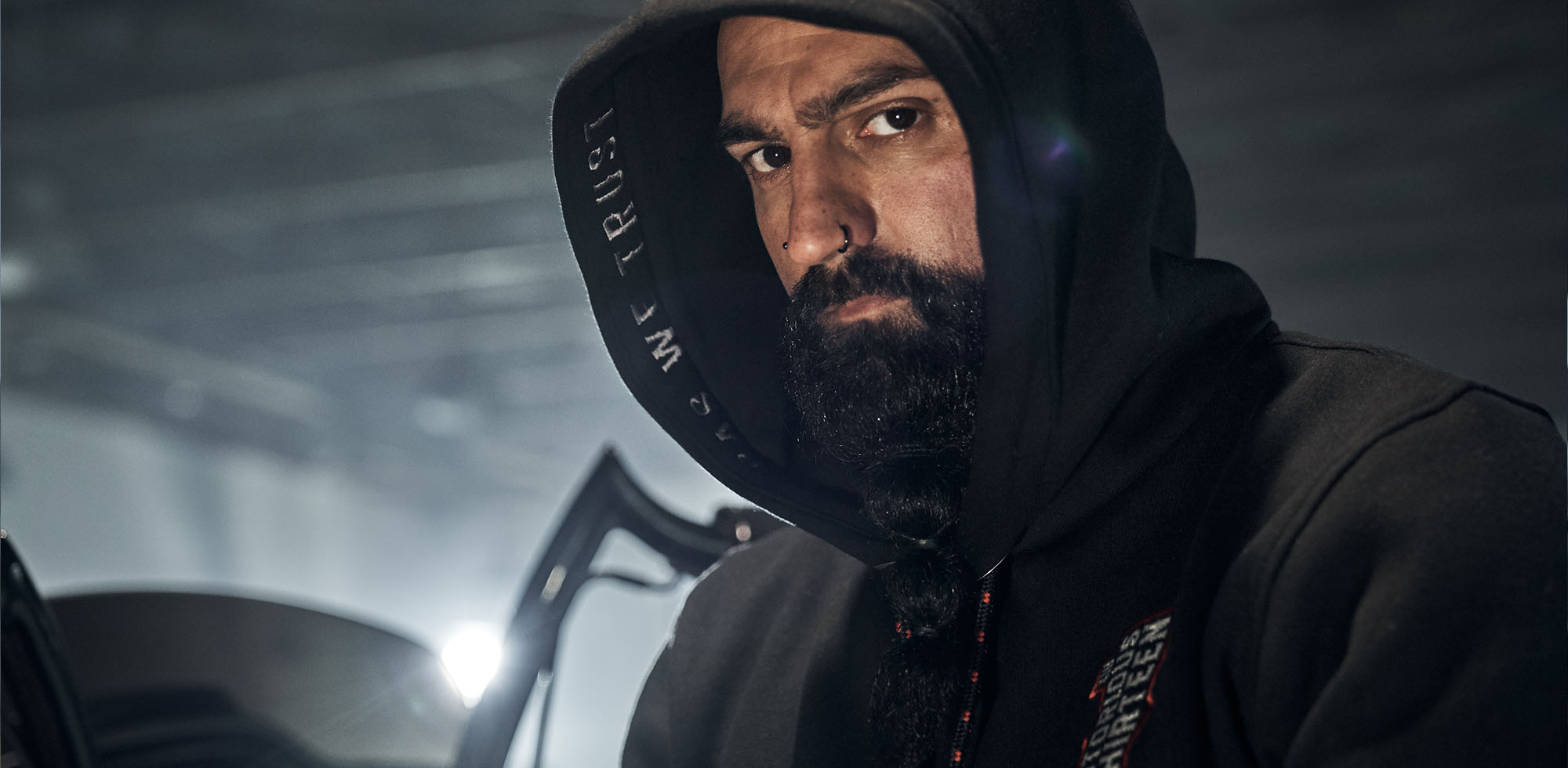 mann mit bart trägt kaputzenpulli von men of mayhem in schwarz