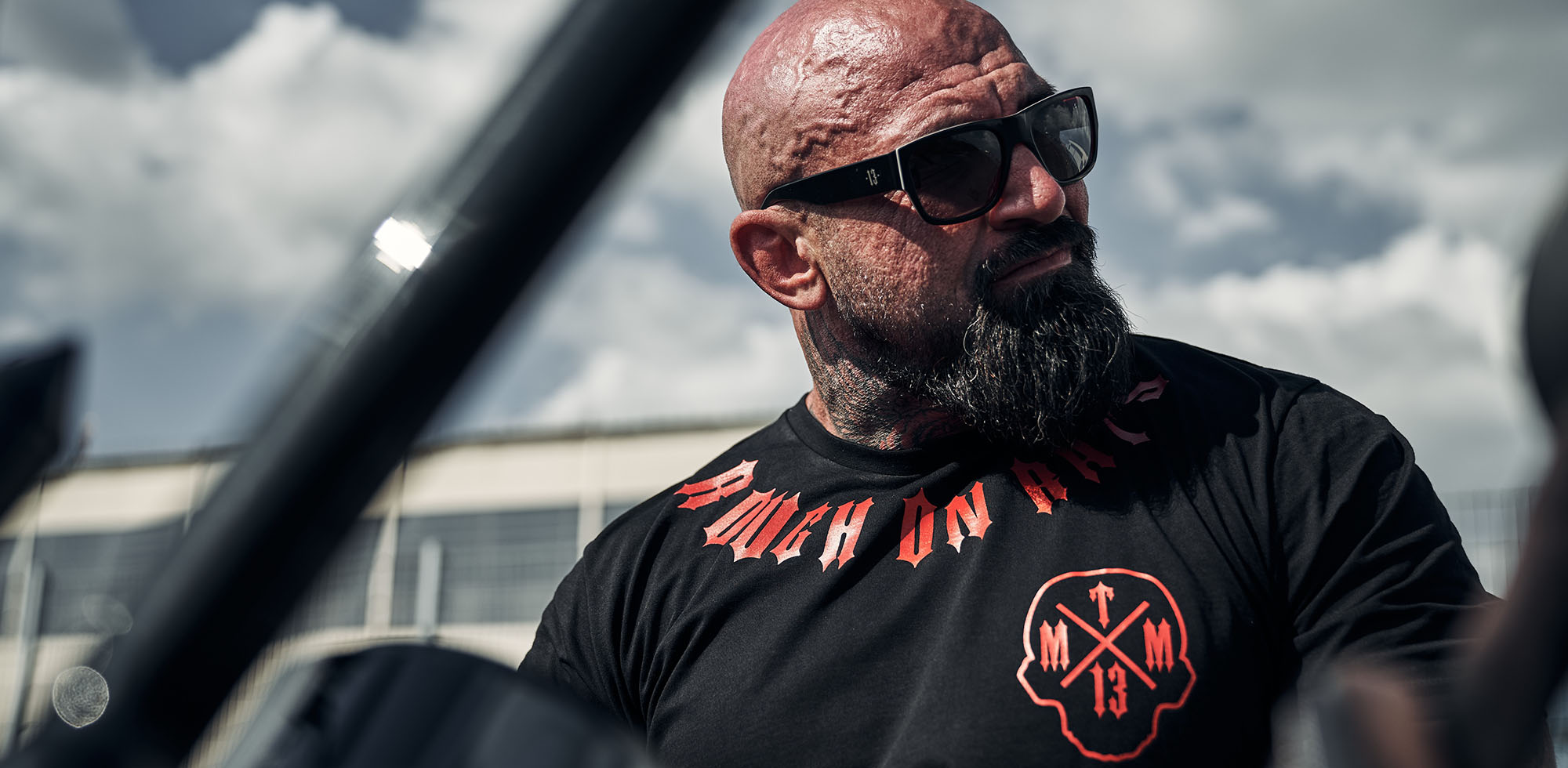 mann sitzend auf harley davidson trägt men of mayhem t-shirt in schwarz rot und sonnenbrille rage in schwarz