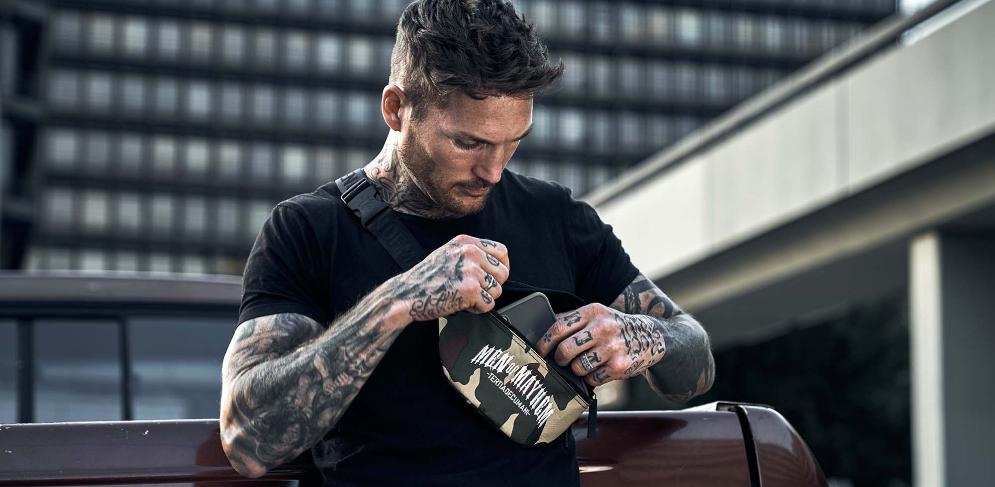 mann stehend trägt men of mayhem bauchtasche in camo mit weißem logo stick