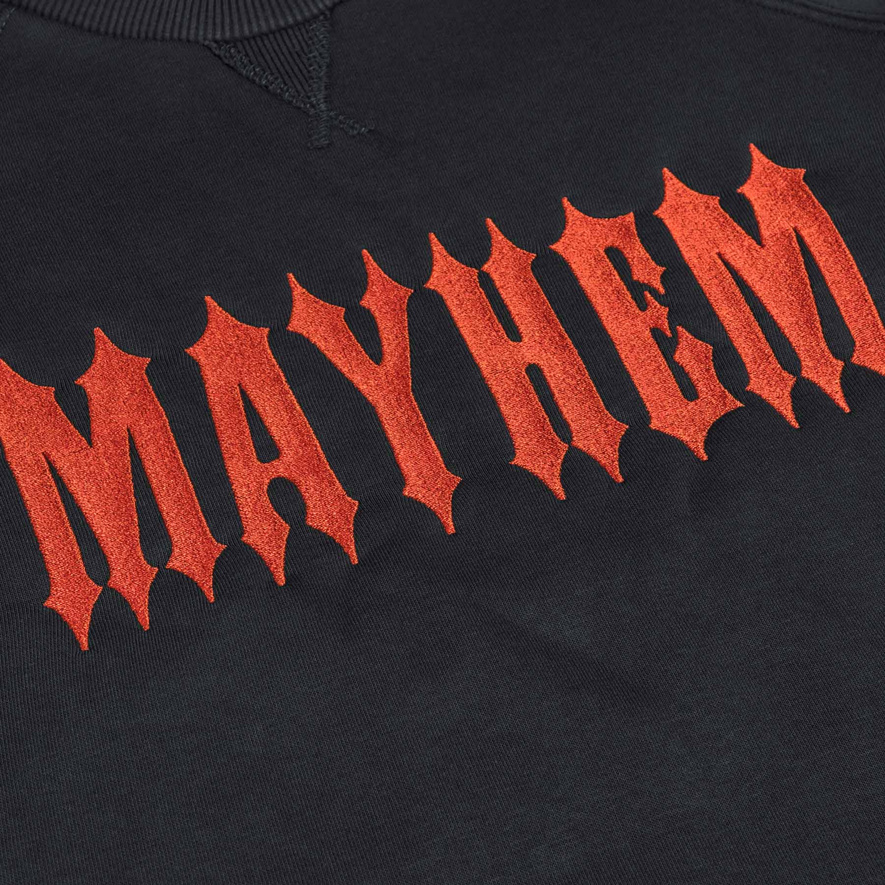 nahaufnahme von einem men of mayhem women crewneck in grau mit orange farbenem stick auf der brust