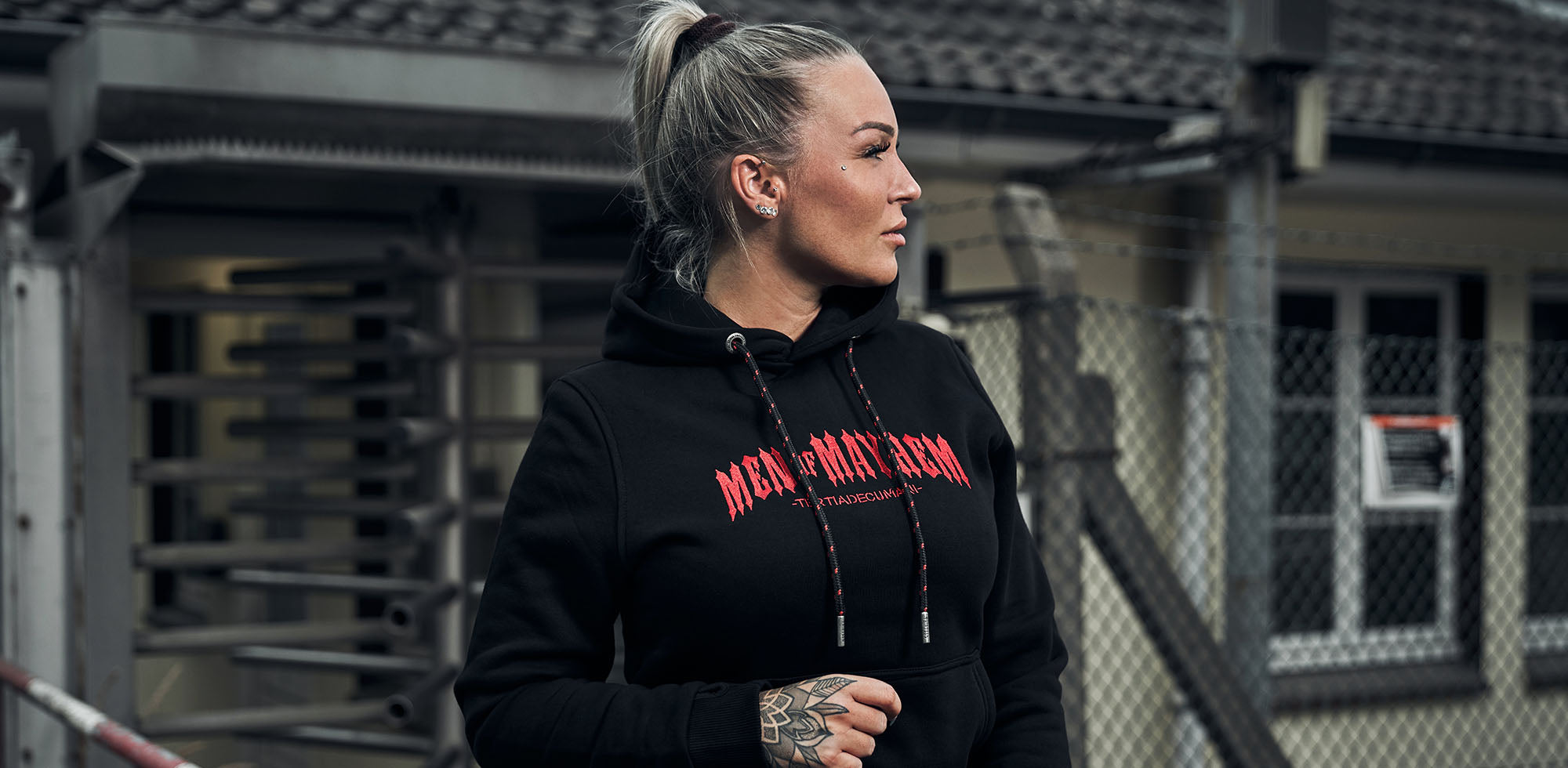 blonde frau stehend trägt men of mayhem classic hoody in schwarz mit rotem logo stick auf der brust
