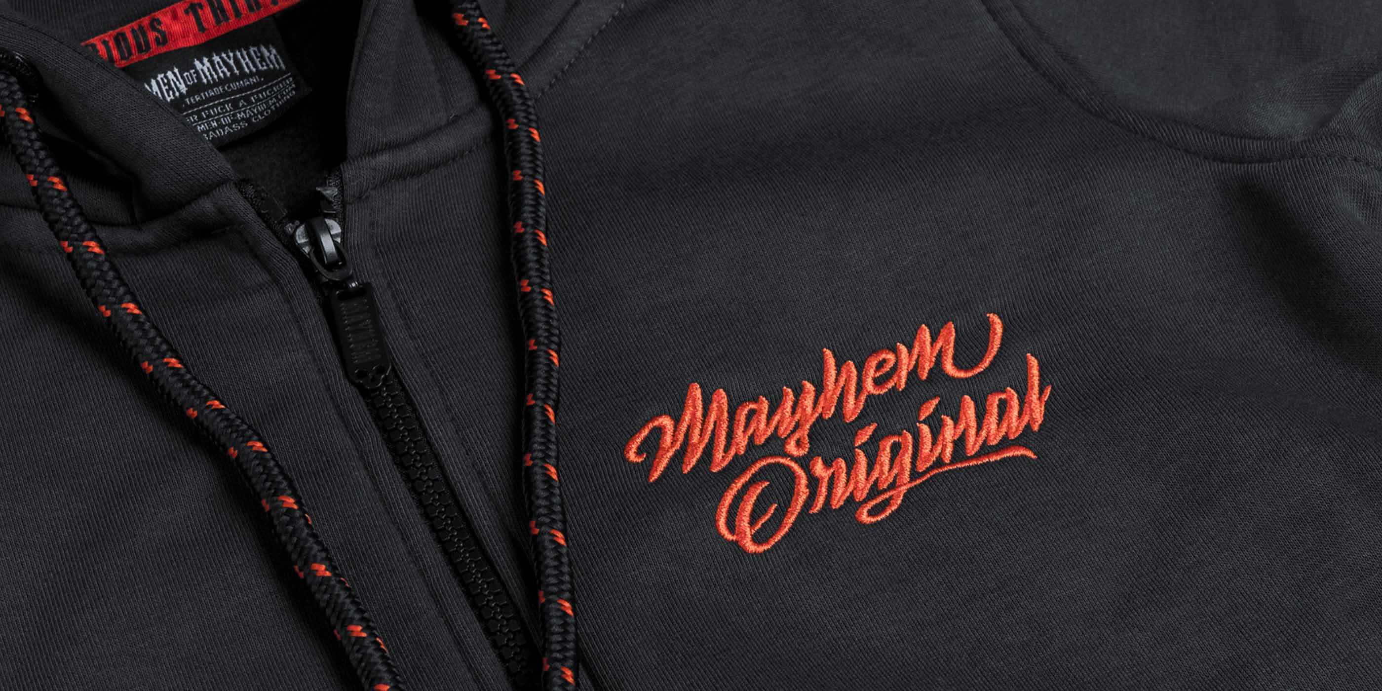 Nahaufnahme eines men of mayhem women zippers modell twof in grau mit orange farbenem stick auf der brust, kapuze und rücken