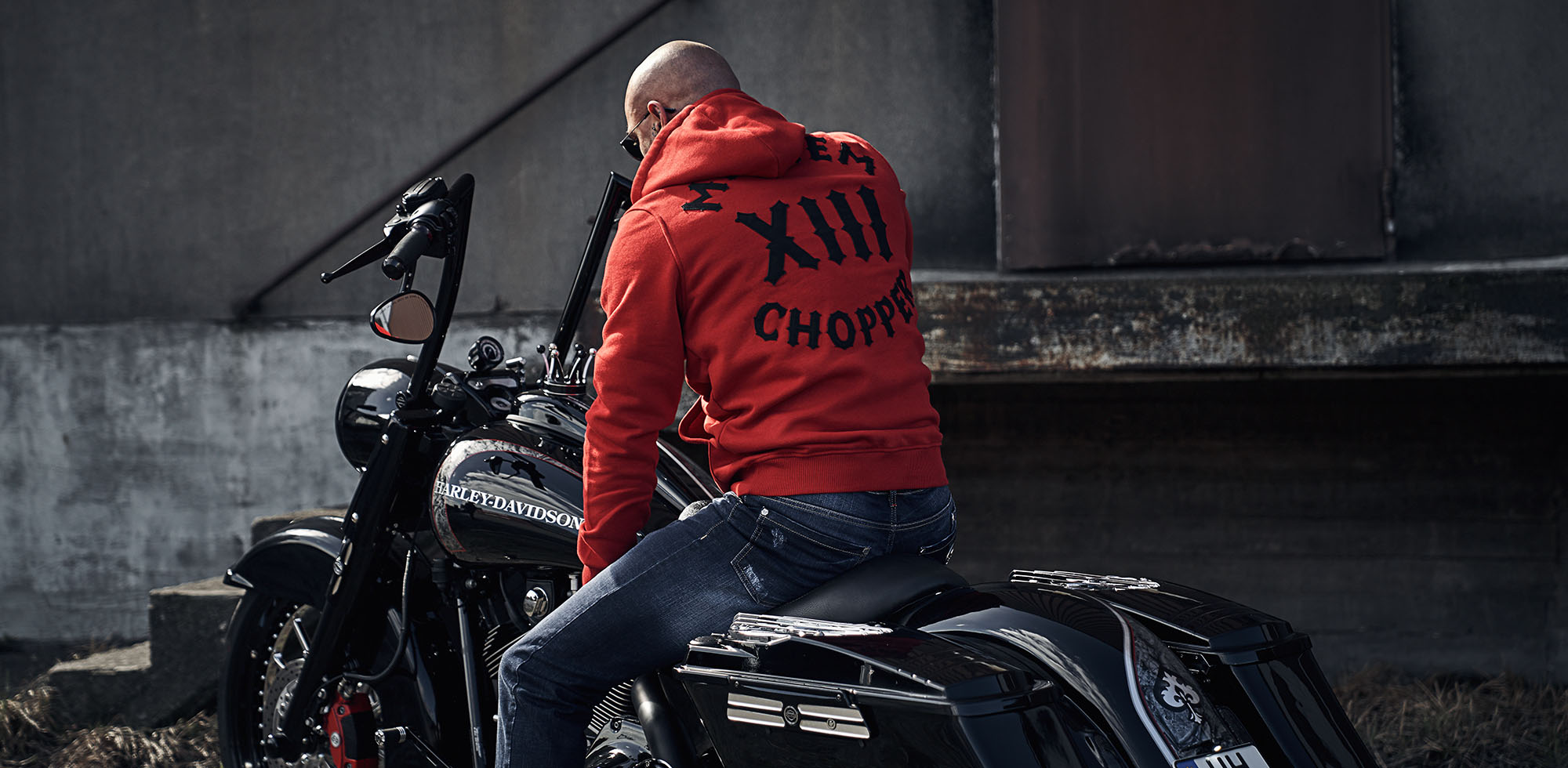 mann sitzend auf schwarzer harley davidson trägt men of mayhem hoody modell chopper in rot mit schwarzer applikation