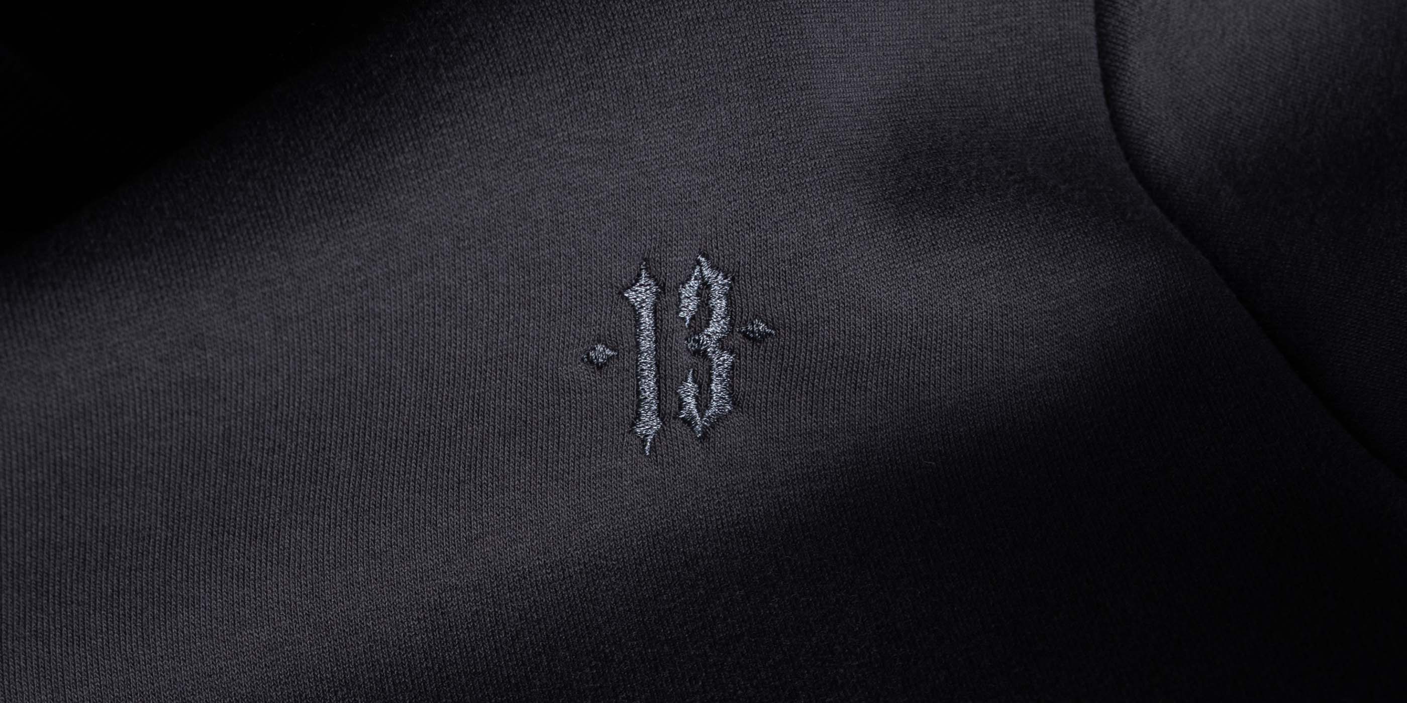 detail aufnahme von men of mayhem crewneck in grau mit gestickter 13 ebenfalls in grau