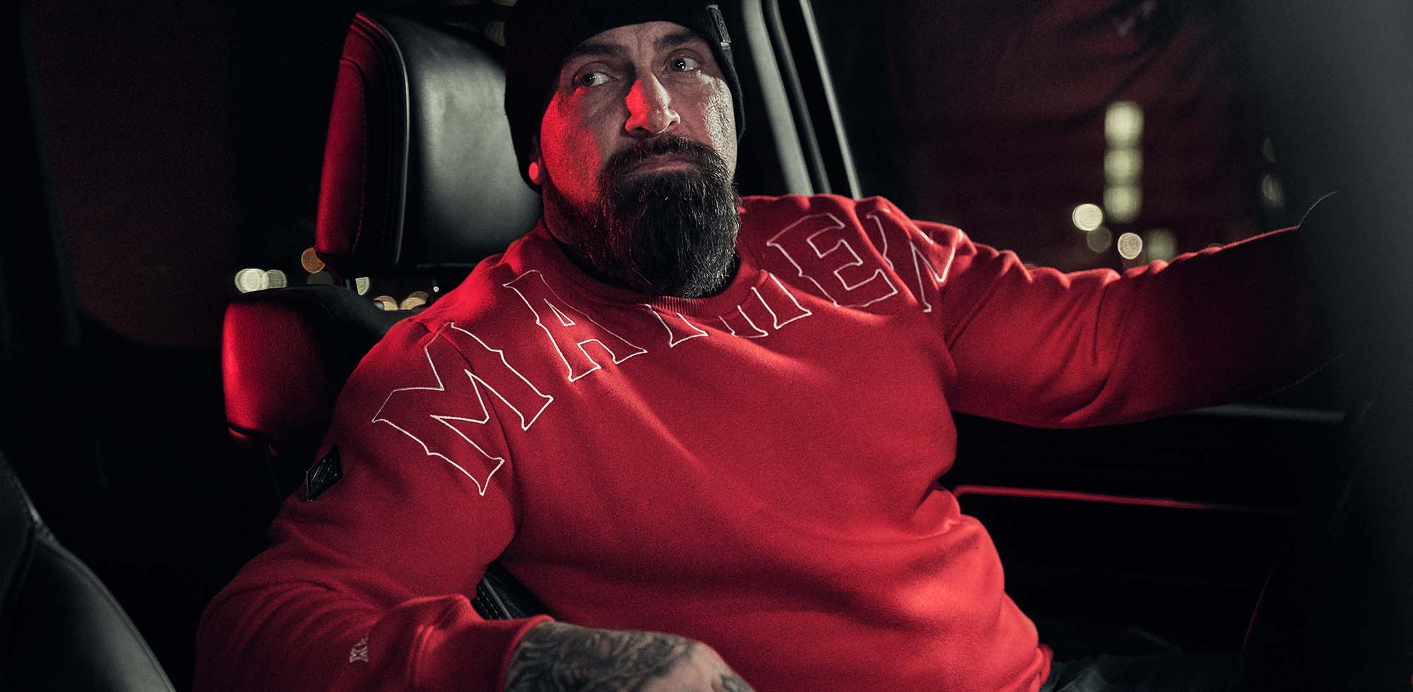 mann sitzend im auto bei nacht trägt men of mayhem crook crewneck in rot weiss