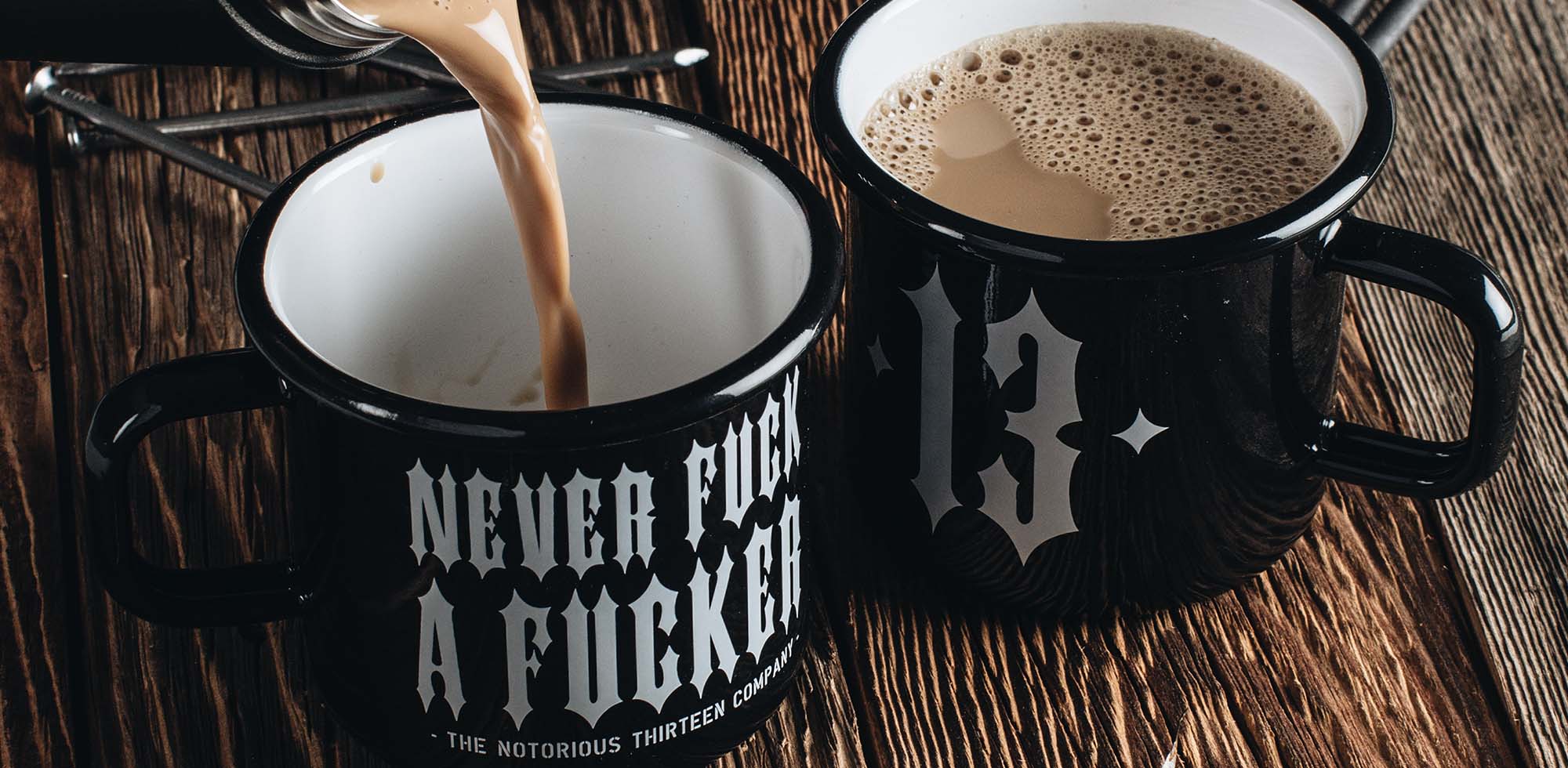 schwarze emaille becher von men of mayhem stehend auf holz mit kaffee