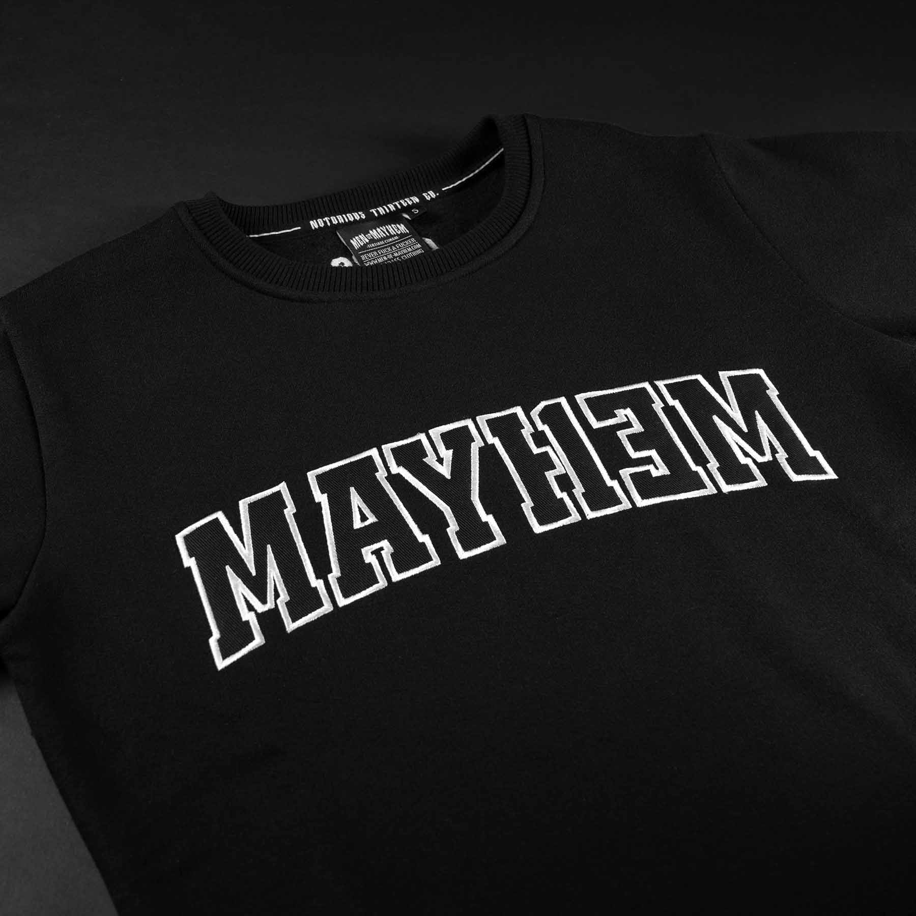 nahaufnahme eines men of mayhem league crewnecks in schwarz mit schwarz weisser aufschrift als applikation 