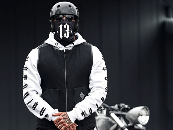 mann stehend trägt helm, men of mayhem weste in schwarz, darunter notorious thirteen hoody in weiß